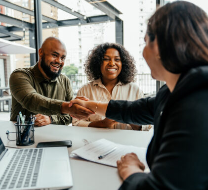 Couple closing real estate contract with real estate agent